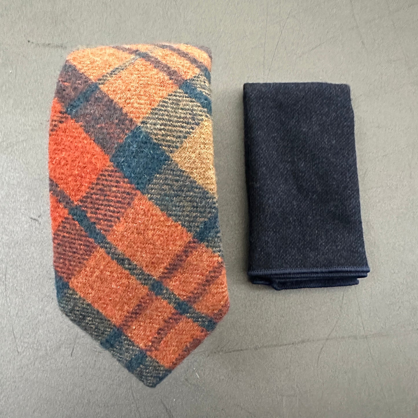 This is an orange wool tie with a navy check paired with a navy wool pocket square. The set makes an ideal gift for men or groomsmen and comes with free gift wrap.