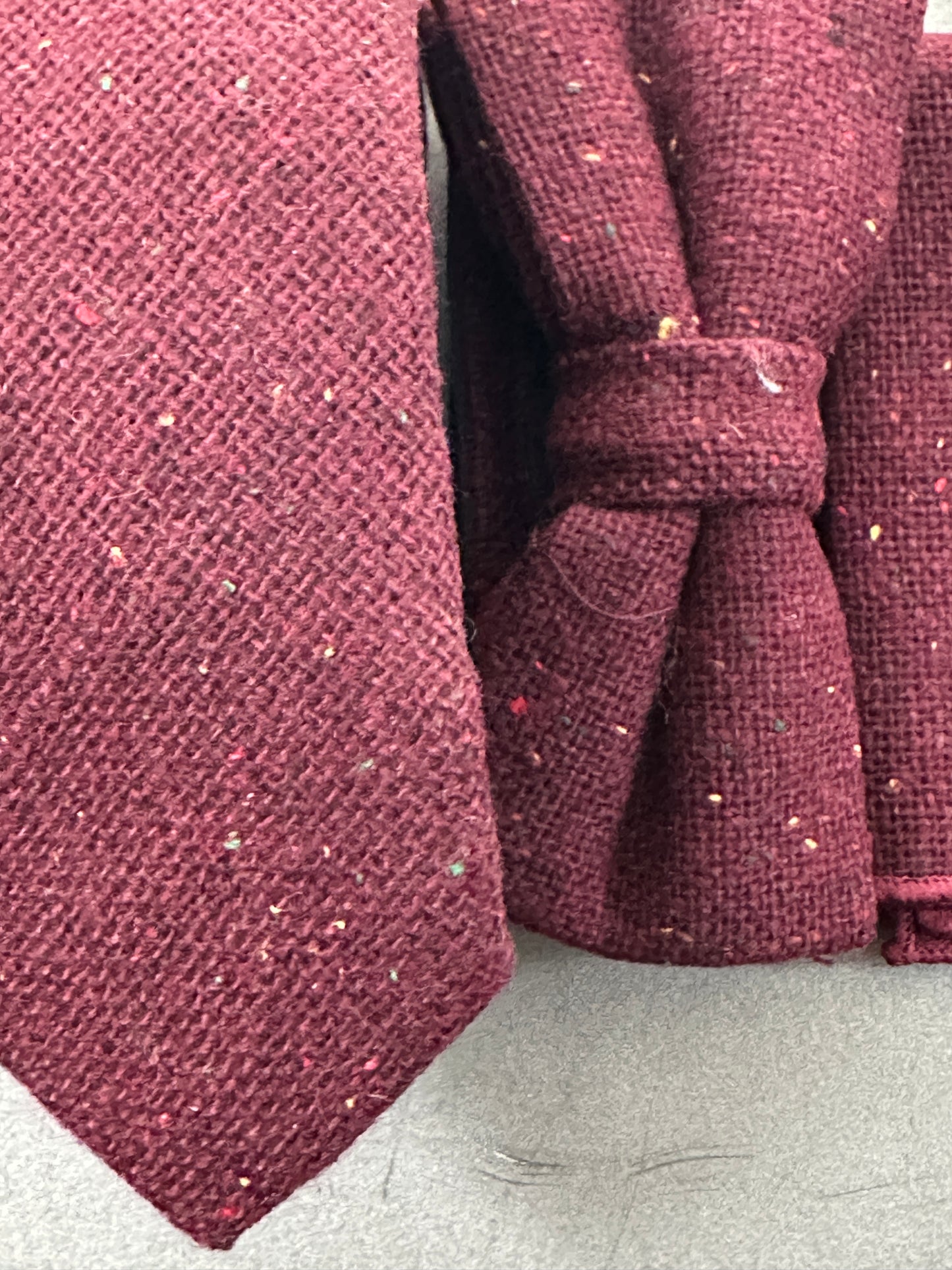 A close up photo of a deep red tie, bow tie and pocket square set ideal for weddings and formal events.