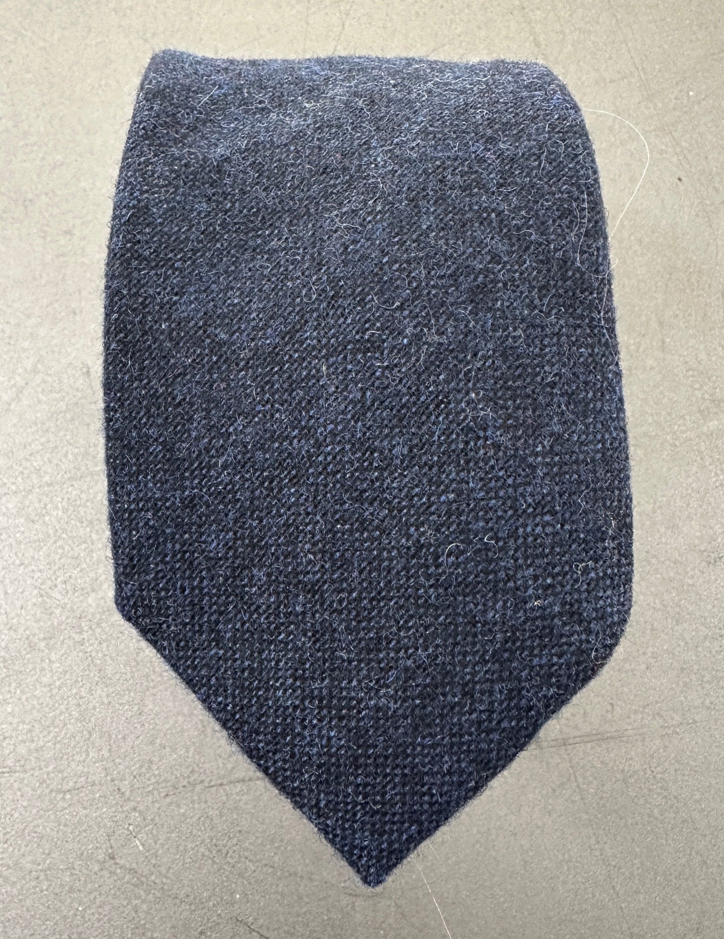 A close up photo of a navy blue mens tie ideal for many occasions including weddings.