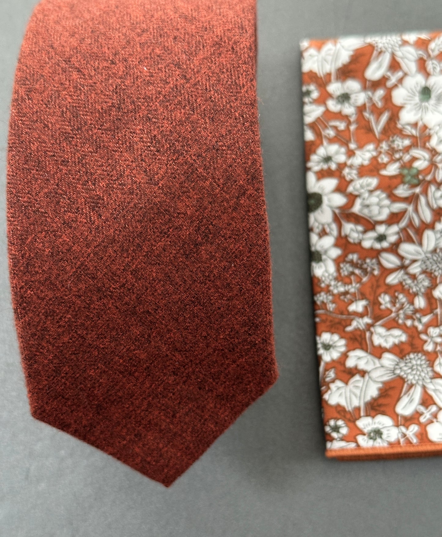 A close up photo of a burnt orange mens tie and pocket square set ideal for wedding ties.
