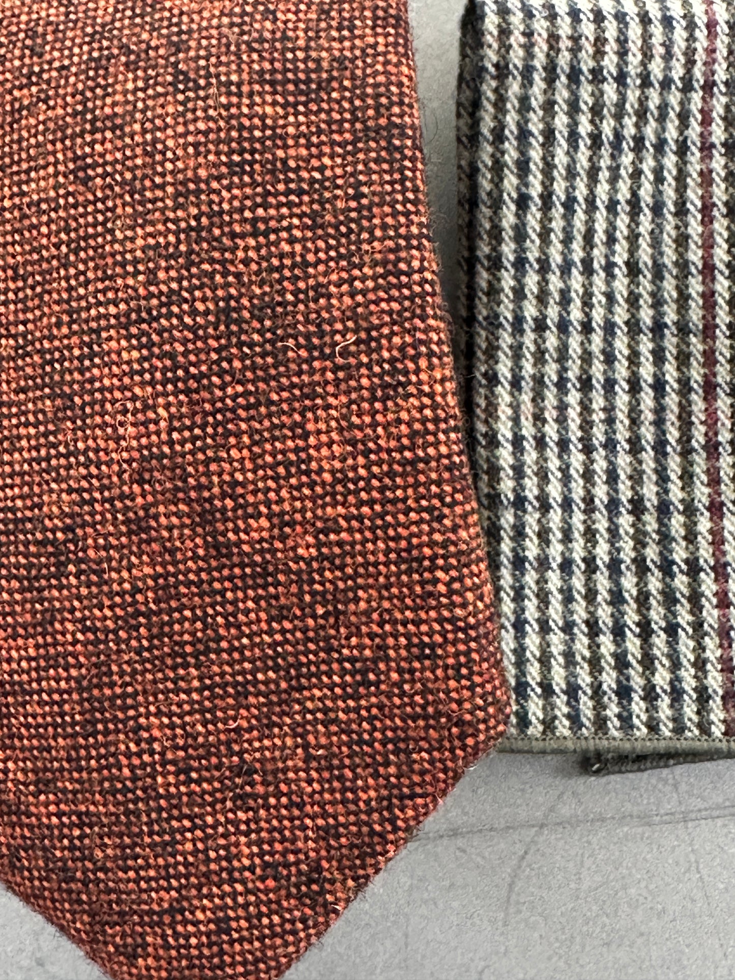 A burnt orange and black flecked mens tie and wool check pocket square.