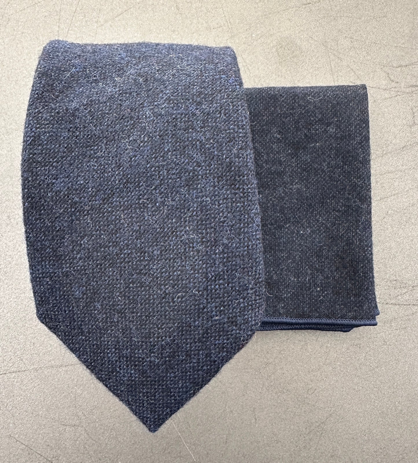 A close up photo of a navy blue mens tie and a blue wool pocket square ideal for many occasions including weddings.