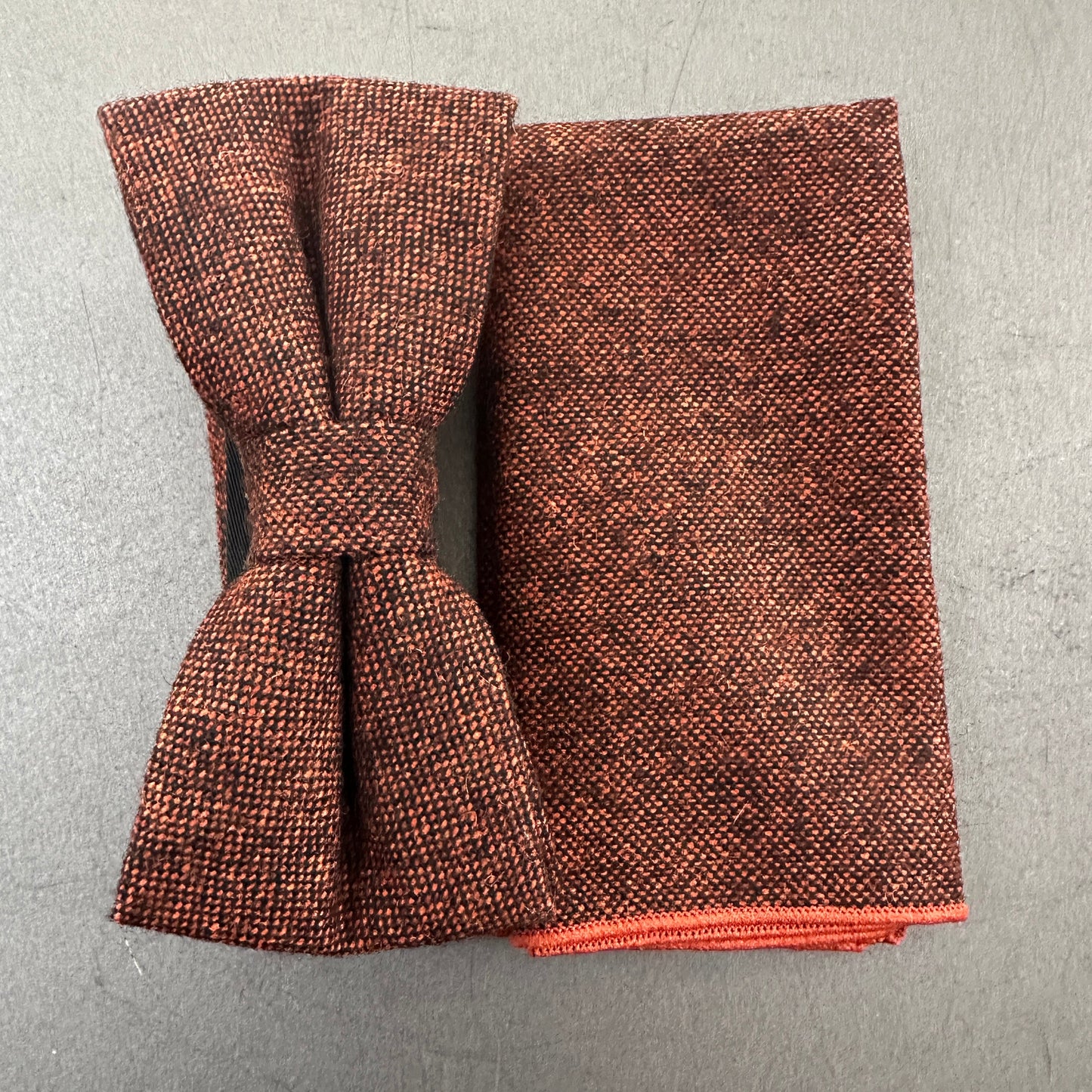 Burnt orange wool bow tie and pocket square set with black flecks, perfect for weddings, groomsmen, and formal wear. This versatile set works beautifully with navy and royal blue suits. The pocket square doubles as a stylish EDC hank, combining practicality with timeless style.