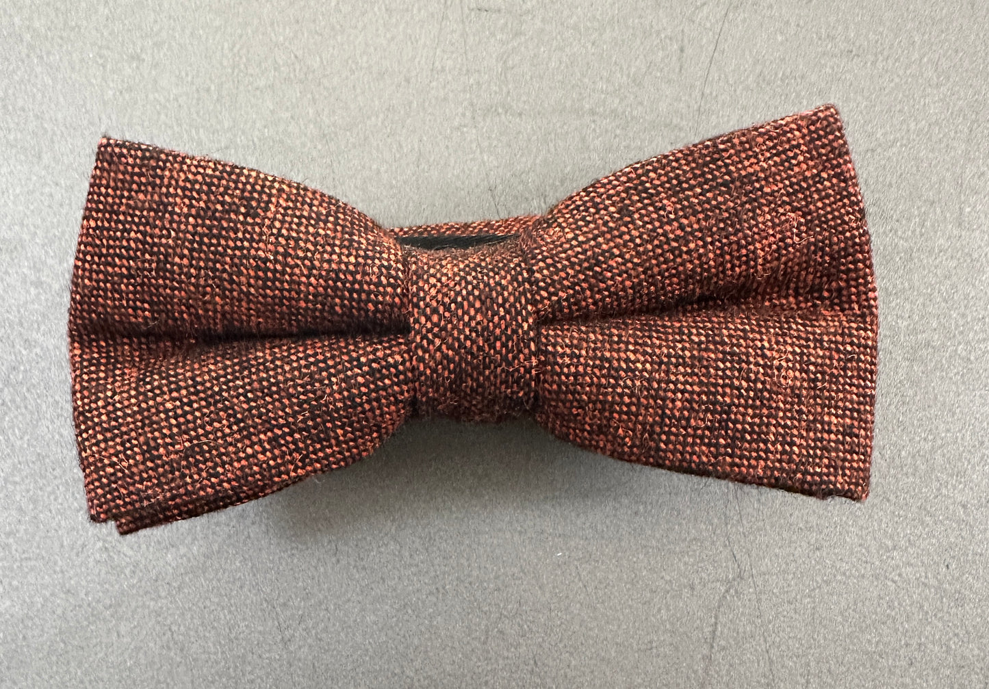 Burnt orange wool bow tie with black flecks, ideal for grooms, groomsmen, and formal wear. This timeless piece pairs perfectly with navy and royal blue suits. Matching wool necktie and pocket square, also available, complete the look.