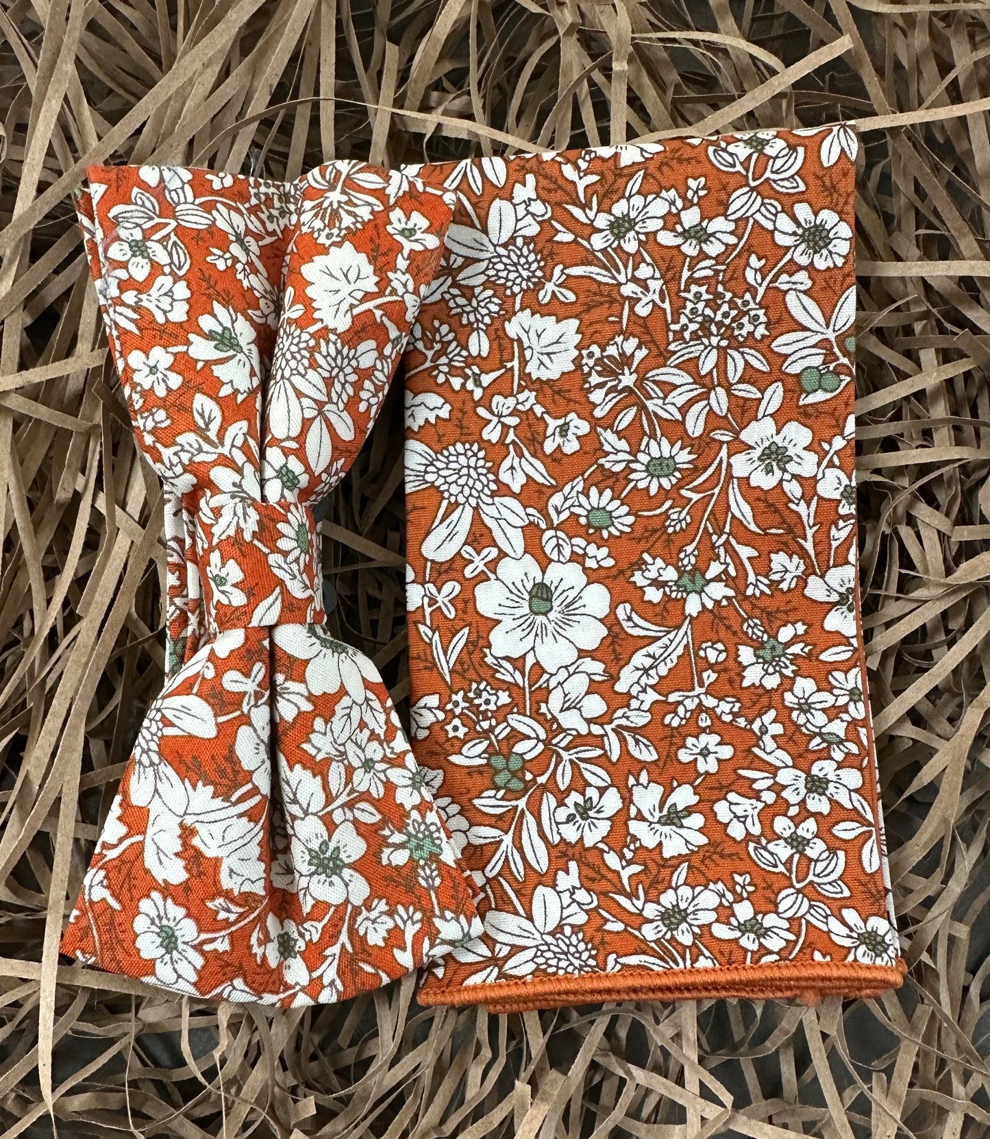 An orange floral bow tie and pocket square set for men.