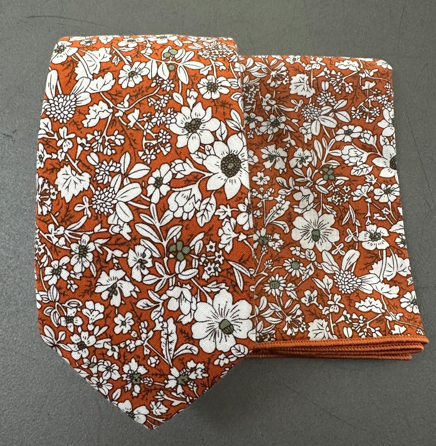 An orange floral tie and pocket square set for men.
