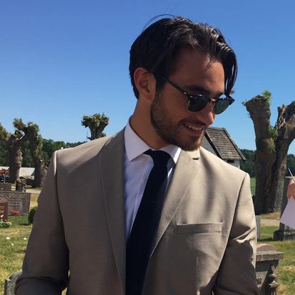 A groomsman at a wedding wearing a handmade navy knitted necktie. The tie is teamed with a beige suit and is perfect as a mans Christmas gift. By Daisy and Oak Studios.