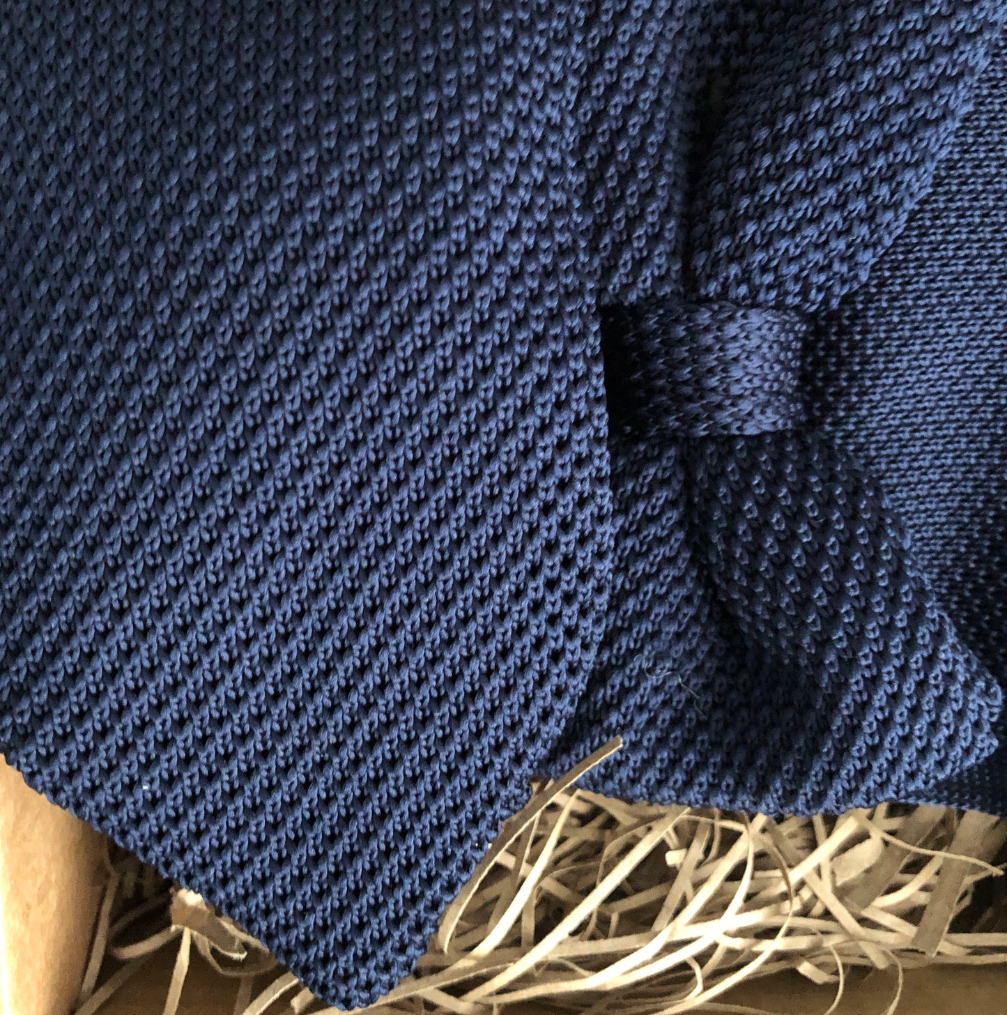 A photo of a navy knitted necktie, bow tie and pocket square. The tie set is perfect wedding attire or as a man's gift and comes with free gift wrapping. Made by Daisy and Oak Studios.