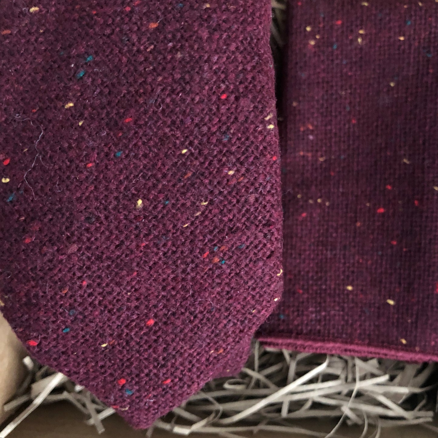 A close up photo of a burgundy flecked wool men's necktie and pocket square. The set comes gift wrapped and makes the best men's Christmas gift, grooms gift and groomsmen's gift.