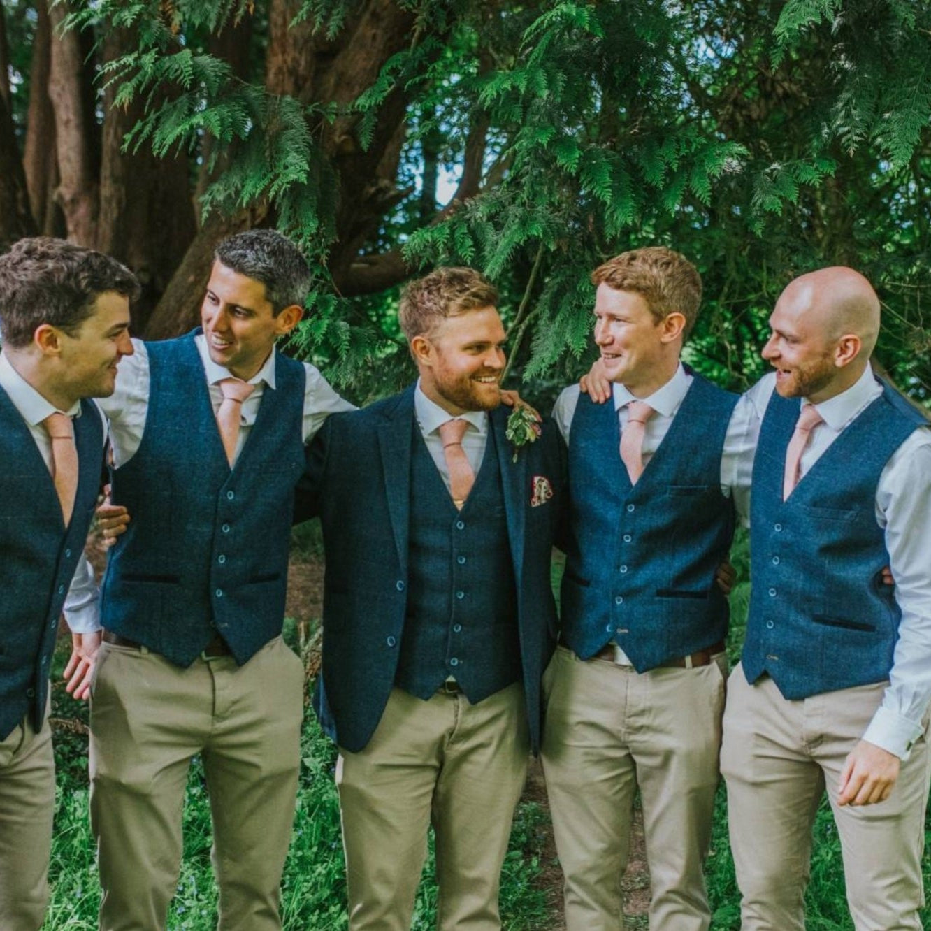 A photo of 5 groomsmen at a wedding wearing a blush pink tie, bow tie and pocket square by Daisy and Oak Studio. The tie is made of wool and comes beautifully gift wrapped so is perfect for men's gifts, wedding ties and groomsmen's gifts.