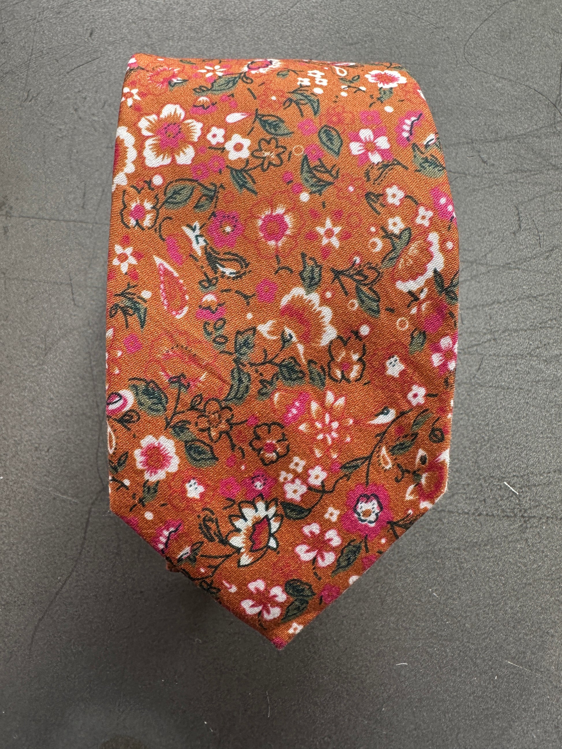 An image of a floral cotton burnt orang, pink and green tie for weddings and mens gifts.