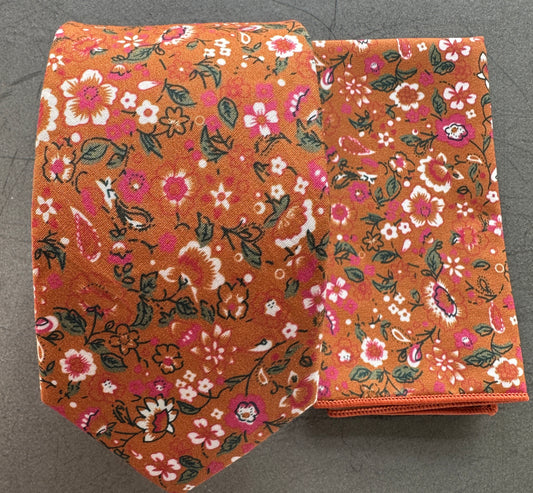 An image of an orange floral tie with pink flowers and hints of green foliage.