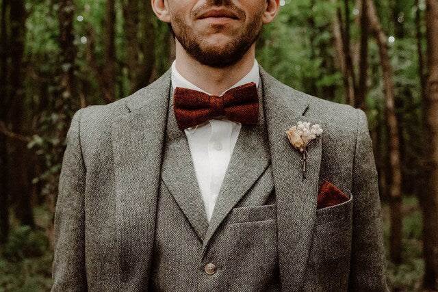 A groom wearing a burnt orange wool bow tie.
