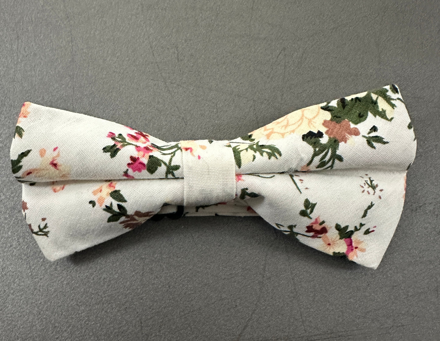 A pink rose. child's bow tie for weddings. The set is made in cotton and is on a cream background.