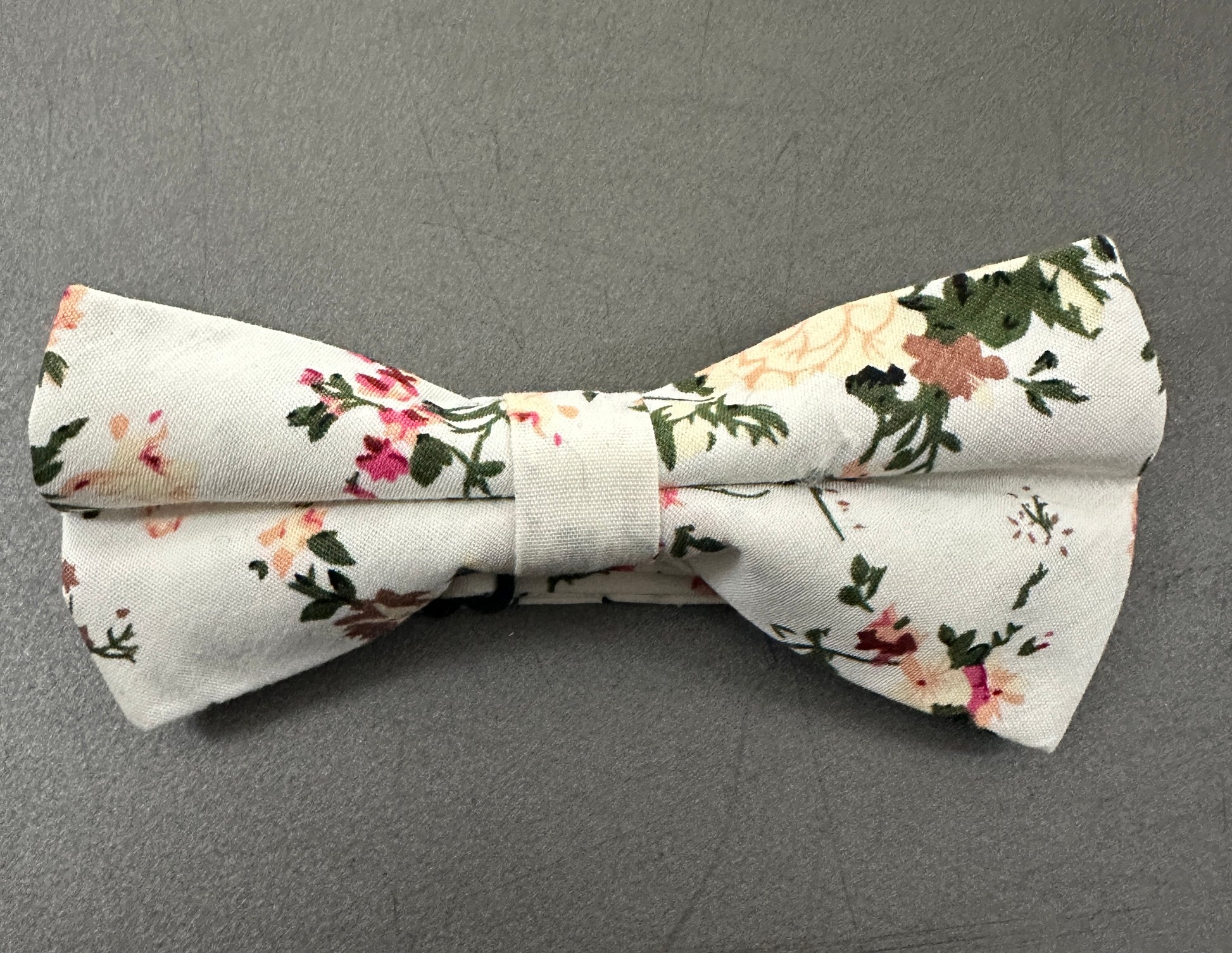 A pink rose. child's bow tie for weddings. The set is made in cotton and is on a cream background.