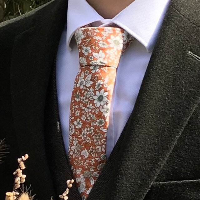 An orange floral tie paired with a white shirt for wedding guests, groomsmen and grooms. The tie also comes with a matching pocket square.