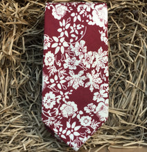 Load image into Gallery viewer, A man&#39;s red floral necktie in cotton . This makes a handsome gift for christmas for men or for a groom and his groomsmen. The tie has a red background with white flowers.