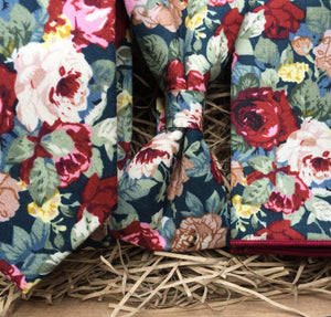 A red cotton tie, bow tie and pocket square set in a floral pattern on a navy background. This set is handmade at the Daisy and Oak Studio, UK 