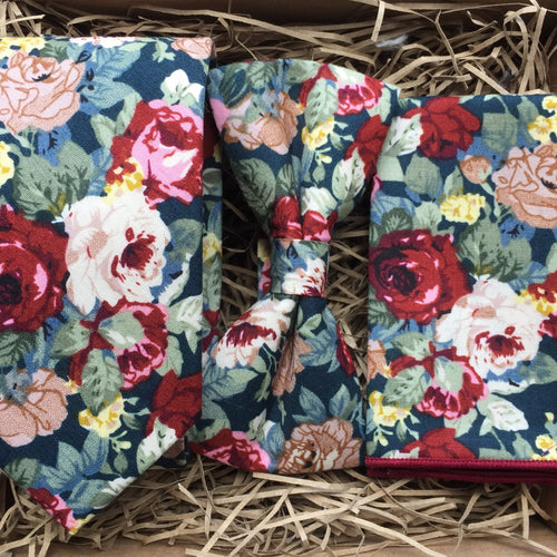 A red cotton tie, bow tie and pocket square set in a floral pattern on a navy background. This set is handmade at the Daisy and Oak Studio, UK 