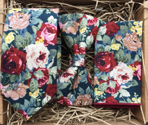 A red cotton tie, bow tie and pocket square set in a floral pattern on a navy background. This set is handmade at the Daisy and Oak Studio, UK 