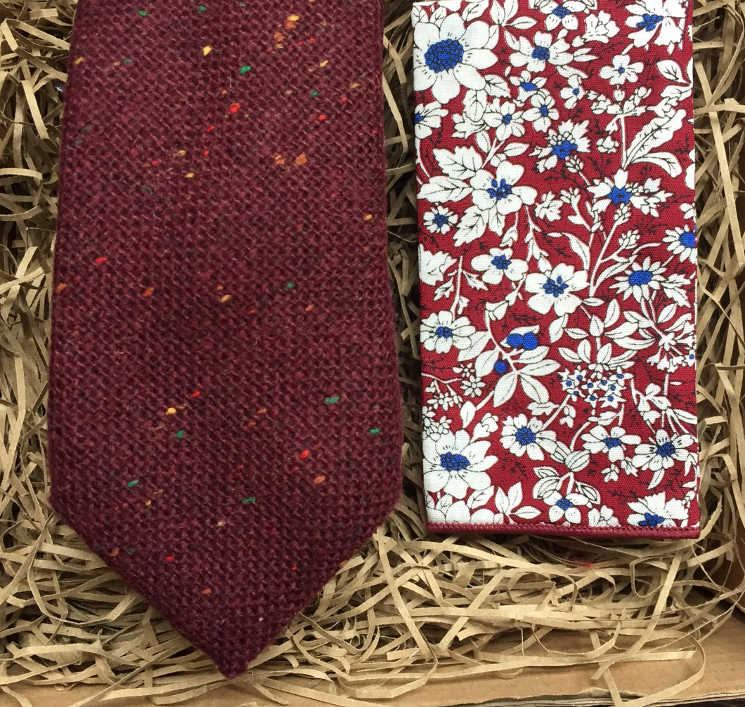 A burgundy red flecked tweed wool men's necktie. Perfect a s a gift wrapped Christmas gift. It is matched with a red floral pocket square and is ideal as a groomsman gift or wedding tie.