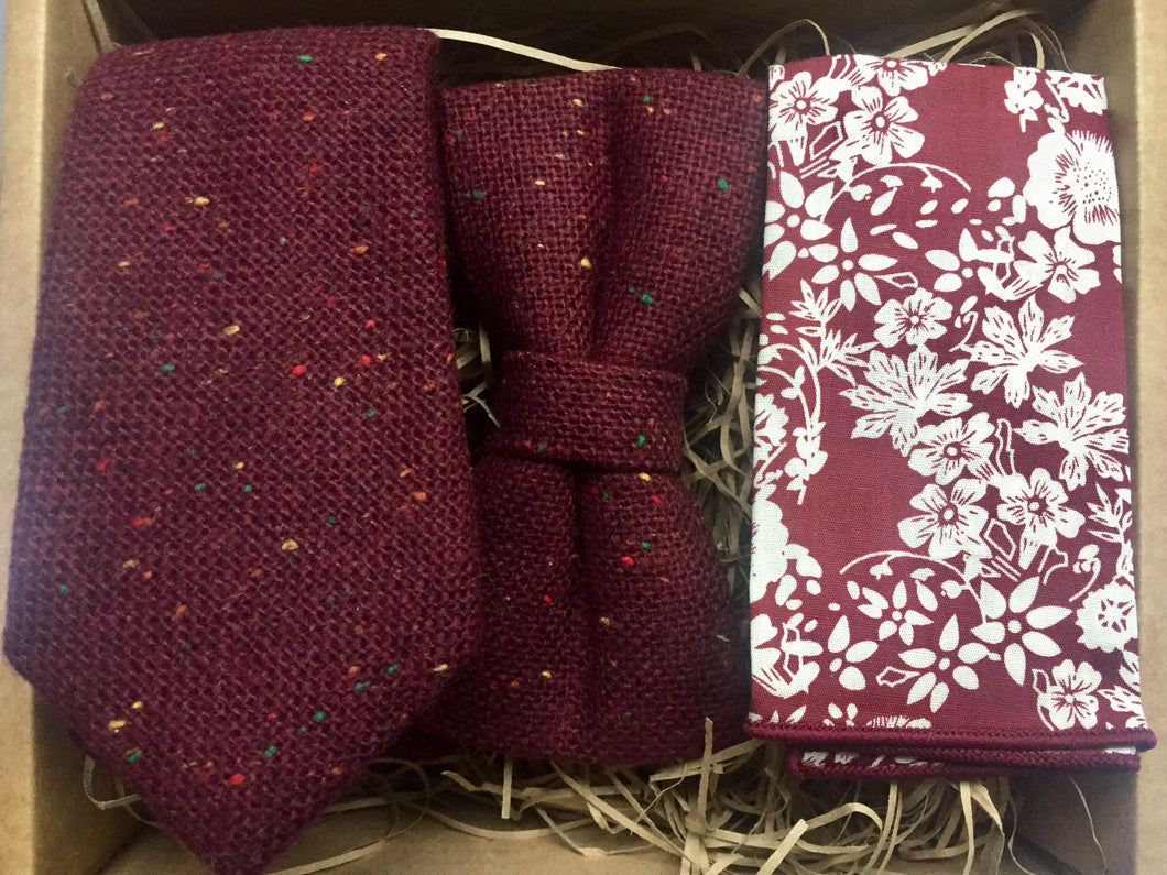 A red, flecked wool tie, bow tie and pocket square set. The tie is burgundy with red, yellow and green flecks. The set comes beautifully gift wrapped and makes an ideal men's gift. The set is made at the Daisy and Oak Studio.