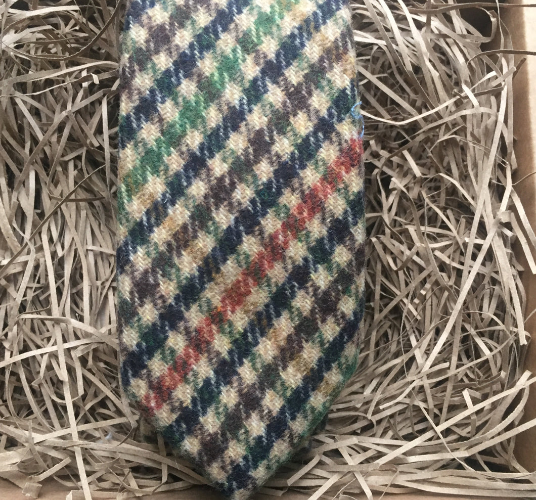 A photo of a mens necktie in a houndstooth pattern. The colours in the tie are green, brown, navy and burnt orange. This is a beautiful necktie and comes gift wrapped and so makes a fabulous men's gift  or secret Santa. IT is also often used as a wedding tie, groomsmen gift or grooms tie paired with  a tween suit.