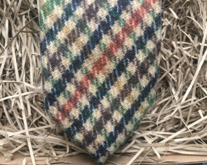 A close up photo of a mens necktie in a houndstooth pattern. The colours in the tie are green, brown, navy and burnt orange. This is a beautiful necktie and comes gift wrapped and so makes a fabulous men's gift or secret Santa. It is also often used as a wedding tie, groomsmen gift or grooms tie paired with a tween suit.