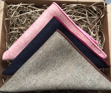 A photo of three inspired wool pocket squares in pink. navy blue and beige. The set makes a perfect gift for men as it is gift wrapped. t could also be a men's secret Santa gift, groomsmen or groom's gift. By Daisy and Oak Studio.