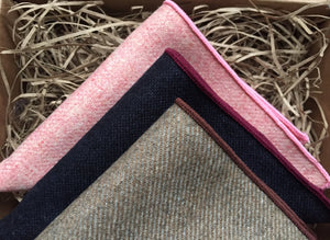 A photo of three inspired wool pocket squares in pink. navy blue and beige. The set makes a perfect gift for men as it is gift wrapped. t could also be a men's secret Santa gift, groomsmen or groom's gift. By Daisy and Oak Studio.