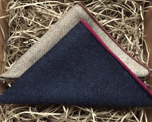 A set of two men's pocket square handkerchiefs in wool. The set has one navy handkerchief with red trim and one beige one. The set is made by hand at Daisy and Oak Studio.
