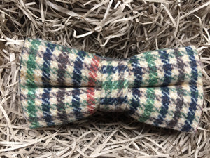 A houndstooth check men's bow tie in wool. THe checks are in a burnt orange, green, brown and navy colour. The bow tie comes gift wrapped and is perfect as men's gift or secret Santa. It is also often used as a groomsmen gift or grooms bow tie paired with a tweed suit.