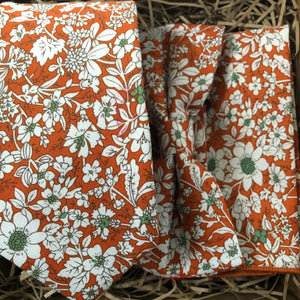 An orange floral tie, bow tie and pocket square ideal for an orange or burnt orange themed wedding. The tie set is handmade by Daisy and Oak Studio