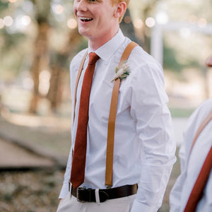 A man at a wedding wearing a burnt orange necktie and braces. The tie comes in rust and terracotta and is perfect as a man's Christmas gift or as a wedding tie for the groom and groomsmen.