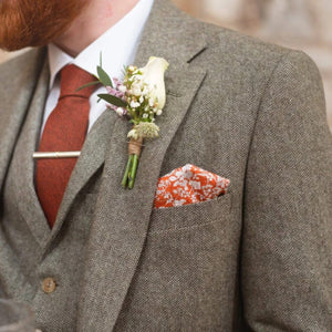 A burnt orange men's necktie matched with an orange floral pocket square and grey herringbone wool suit. This is the perfect men's rust Christmas present or terracotta groomsmen present as it is gift wrapped.