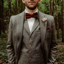 Load image into Gallery viewer, A man&#39;s bow tie in wool. This is a burnt orange wool bow tie ideal as a mans gift or as a wedding bow tie. The photo shows a groom wearing a tweed suit in grey and a white tie. This is a really nice bow tie perfect for any occasion and handmade by Daisy and Oak Studio