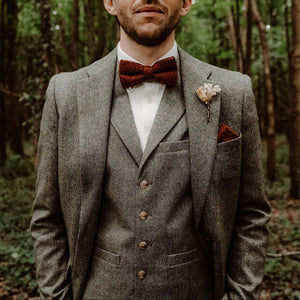 A man's bow tie in wool. This is a burnt orange wool bow tie ideal as a mans gift or as a wedding bow tie. The photo shows a groom wearing a tweed suit in grey and a white tie. This is a really nice bow tie perfect for any occasion and handmade by Daisy and Oak Studio