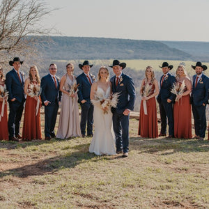 A bride and groom in the desert in the USA. The groom is wearing a blue suit and the Maple burnt orange tie made by Daisy and Oak Studio, UK