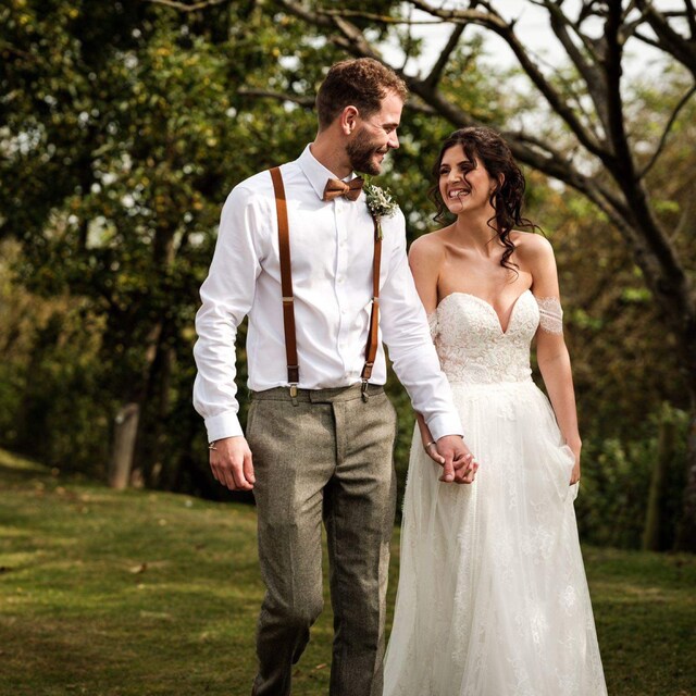 A groom wearing an autumnal burnt-range bow tie and burnt-orange braces.