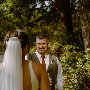 A photo of a groom at a wedding wearing a burnt orange men's necktie. The rust tie is made of cotton and we offer free gift wrapping so is perfect as a wedding tie, men's gift, groomsman gift. Our ties are handmade at the Daisy and Oak Studio.